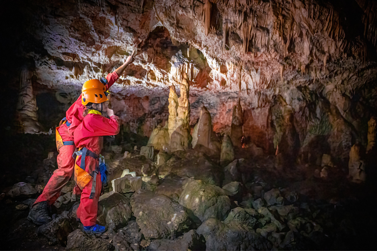 Guide NOA Guides explorant une spectaculaire grotte du Jura avec un groupe