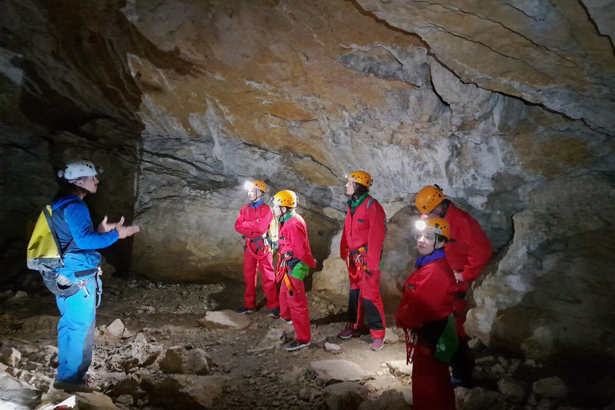 Participants découvrant une grotte du Jura à la température fraîche et stable