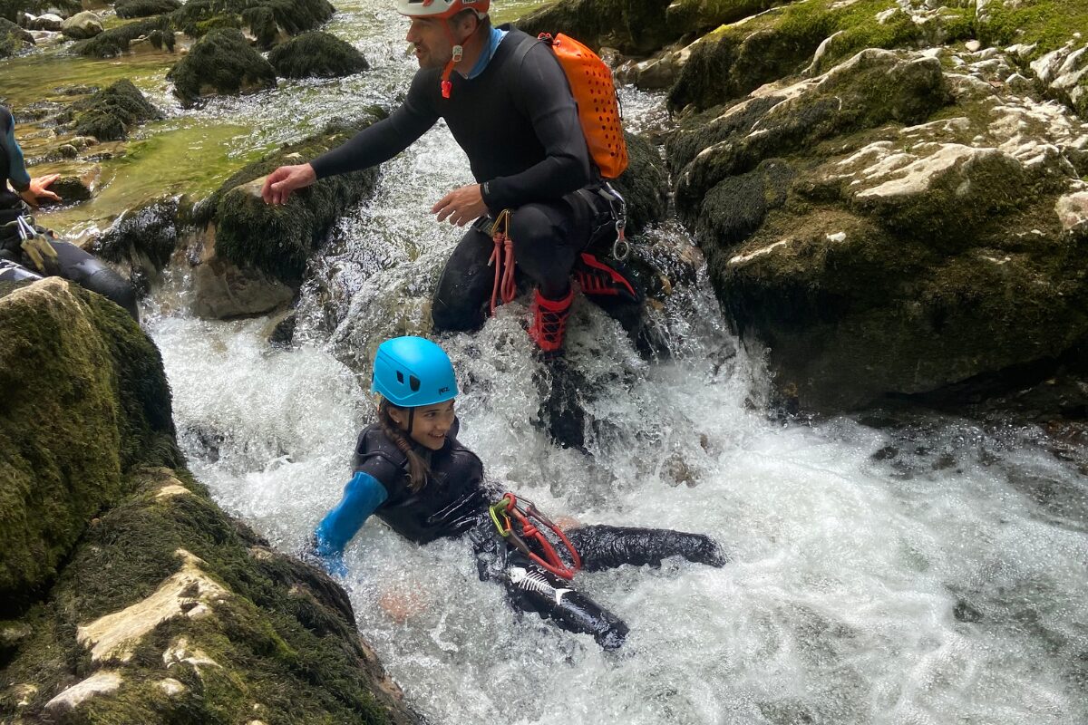 canyoning-enfant-toboggan-jura Enfant descendant un toboggan naturel pendant une sortie canyoning dans le Jura
