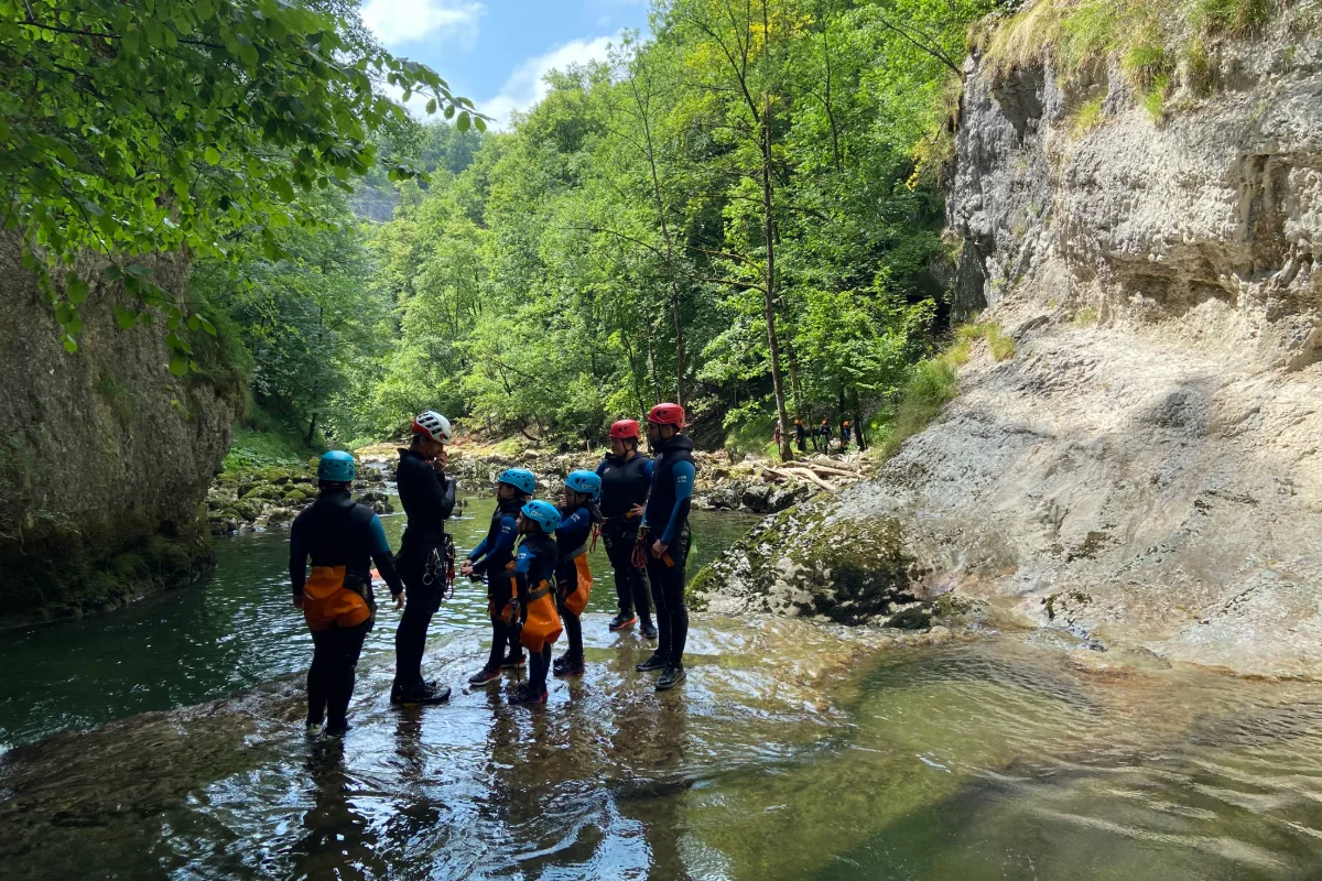 Petit groupe seul dans une rivière entourée de falaises et de forêt, canyon calme dans le Jura