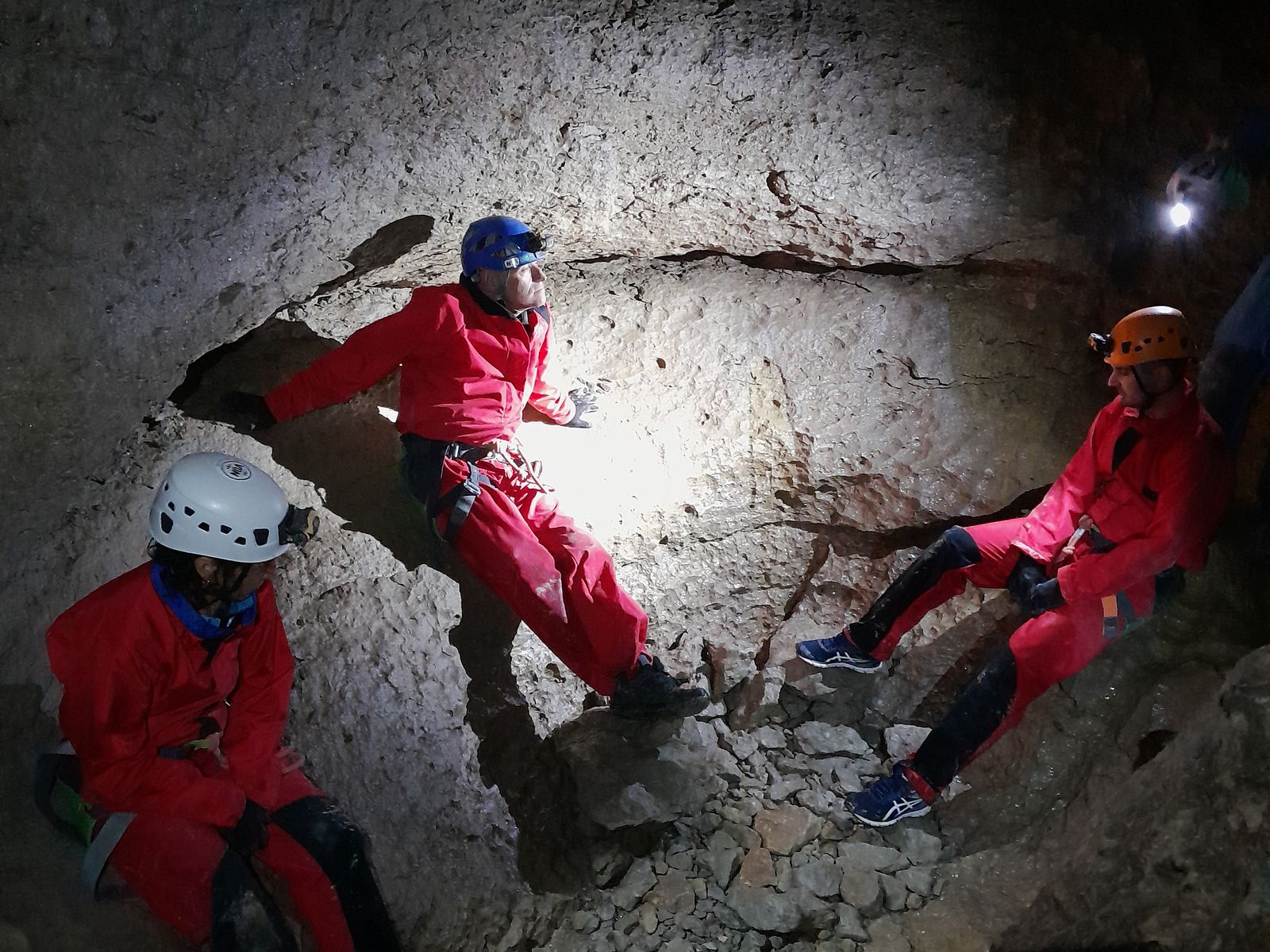 Groupe en combinaison rouge lors d’une initiation à la spéléologie dans la grotte de Balerne
