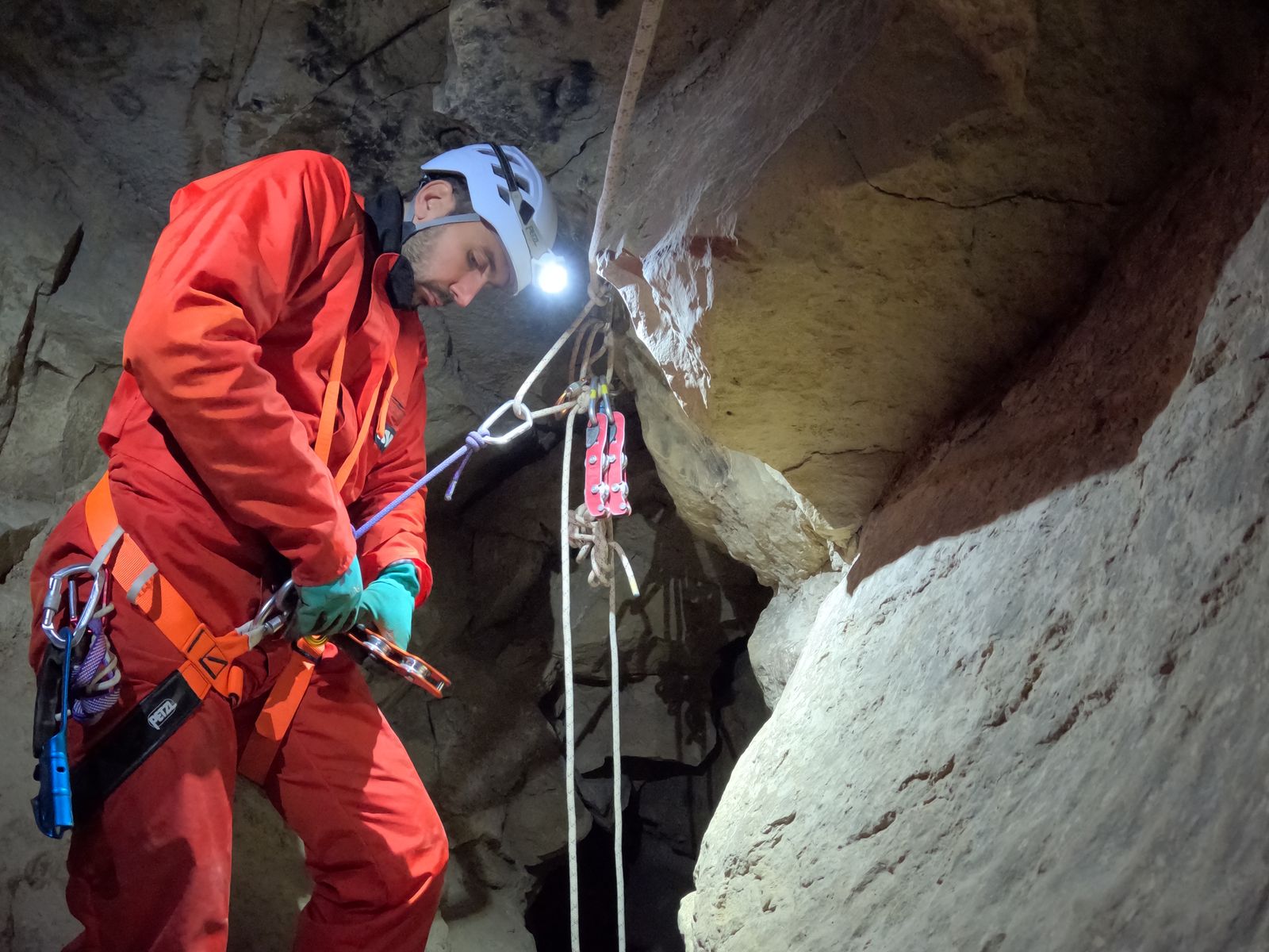 Guide installant une main-courante sur corde dans la grotte de Balerne