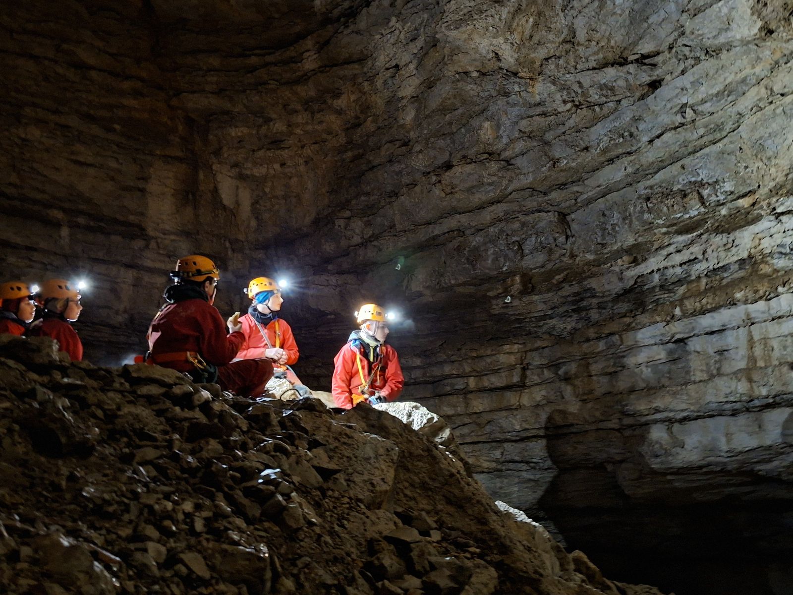 strates-calcaires-gouffre-des-ravieres-jura Spéléologues au pied d’une immense paroi de strates calcaires dans le gouffre des Ravières